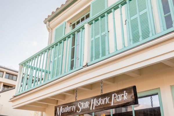 A building with mint green shutters and balcony, with a sign reading 